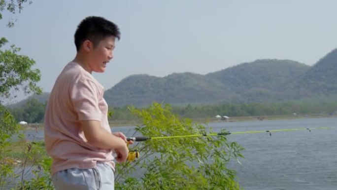 快乐的亚洲男孩在湖边钓鱼，与家庭户外露营，生活方式理念。