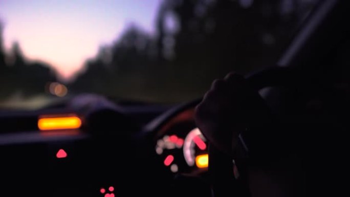 夜间旅行时，驾驶员手放在汽车方向盘上，特写镜头