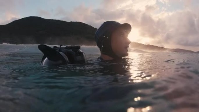 惊讶的冲浪摄影师。戴着蓝色帽子的男人带着运动相机在海里游泳，环顾四周
