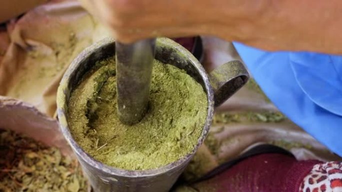 在摩洛哥马拉喀什，用传统的铁砂浆将指甲花叶子磨成粉末。