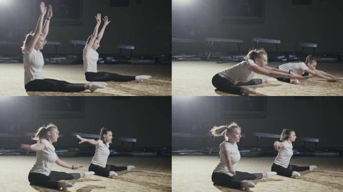 两名运动女子在地板上一起锻炼，向前伸展以触摸脚趾，以健康和健身的概念