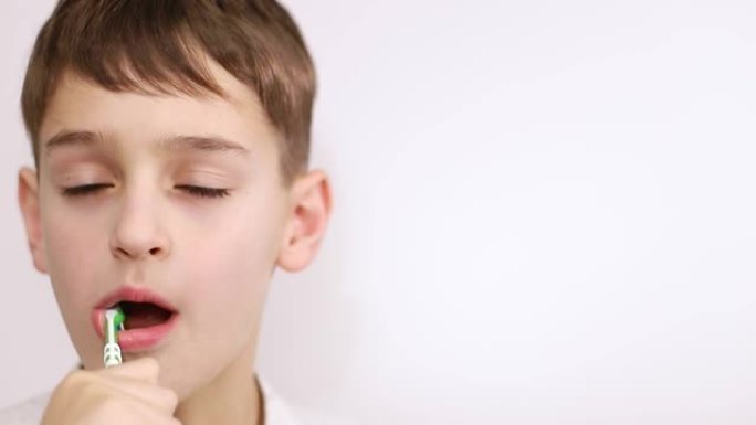小男孩在白色背景上刷牙，健康的嘴的概念