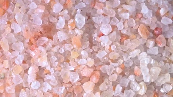 粉色喜马拉雅盐。黑色背景上木勺中的喜玛拉雅粉色岩盐特写。粉色喜马拉雅盐细粒