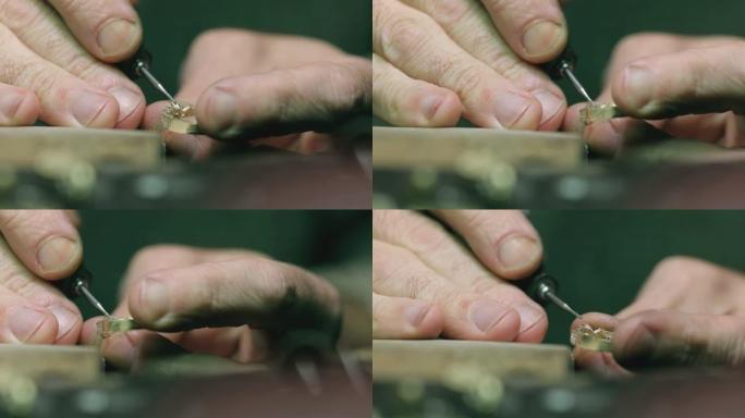 用抛光机和圆形旋转砂纸或旋转工具制作黄色金戒指的人的手。特写镜头。金匠用抛光机抛光银或金戒指
