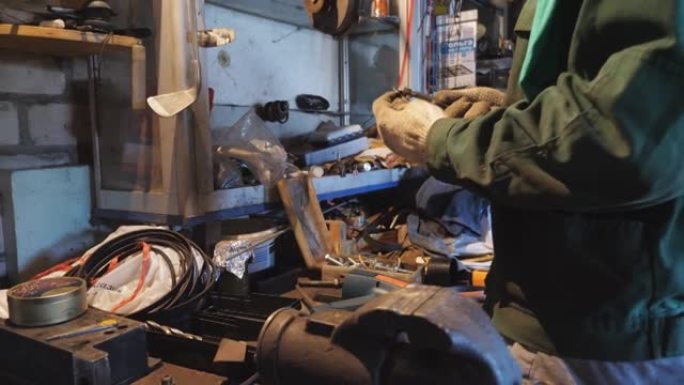 工装的年轻修理工在车间使用工具检查车辆细节。男性机械师在工作场所工作。穿制服的专业修理工在车库工作。
