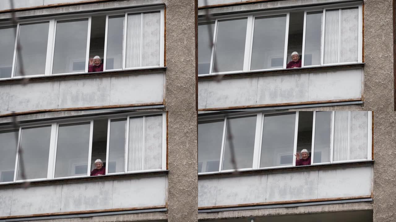 老年妇女从隔离阳台的窗户挥手告别问候