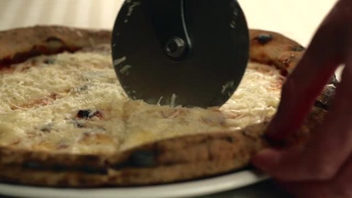 大厨切新鲜背热美味意大利披萨的特写镜头。