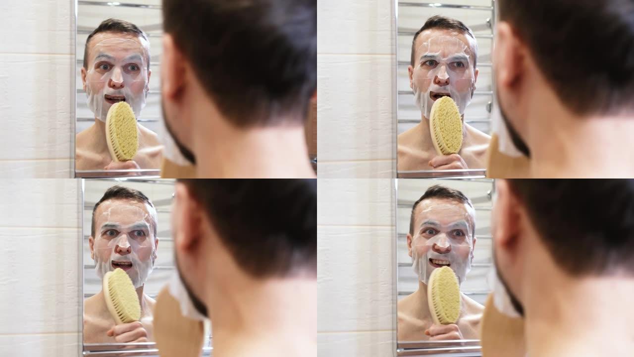 有趣的大胡子男人，戴着化妆品面膜唱歌，在浴室的镜子前玩得开心。在家进行自我护理，健康，良好的心情和水
