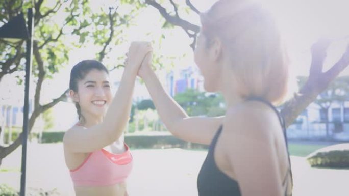 两名年轻的亚洲女运动员朋友在公园握手