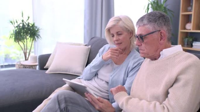 一对老年夫妇在家里沙发上使用数字平板电脑的4k视频片段