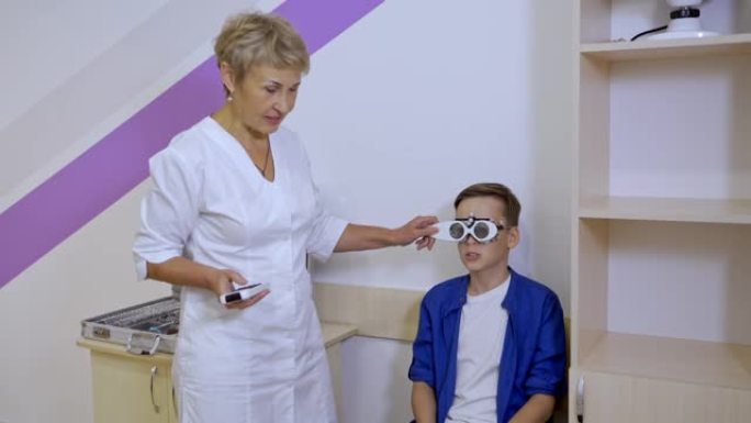 眼科医生和男孩在房间里。在眼科诊所检查视力的男孩的镜头