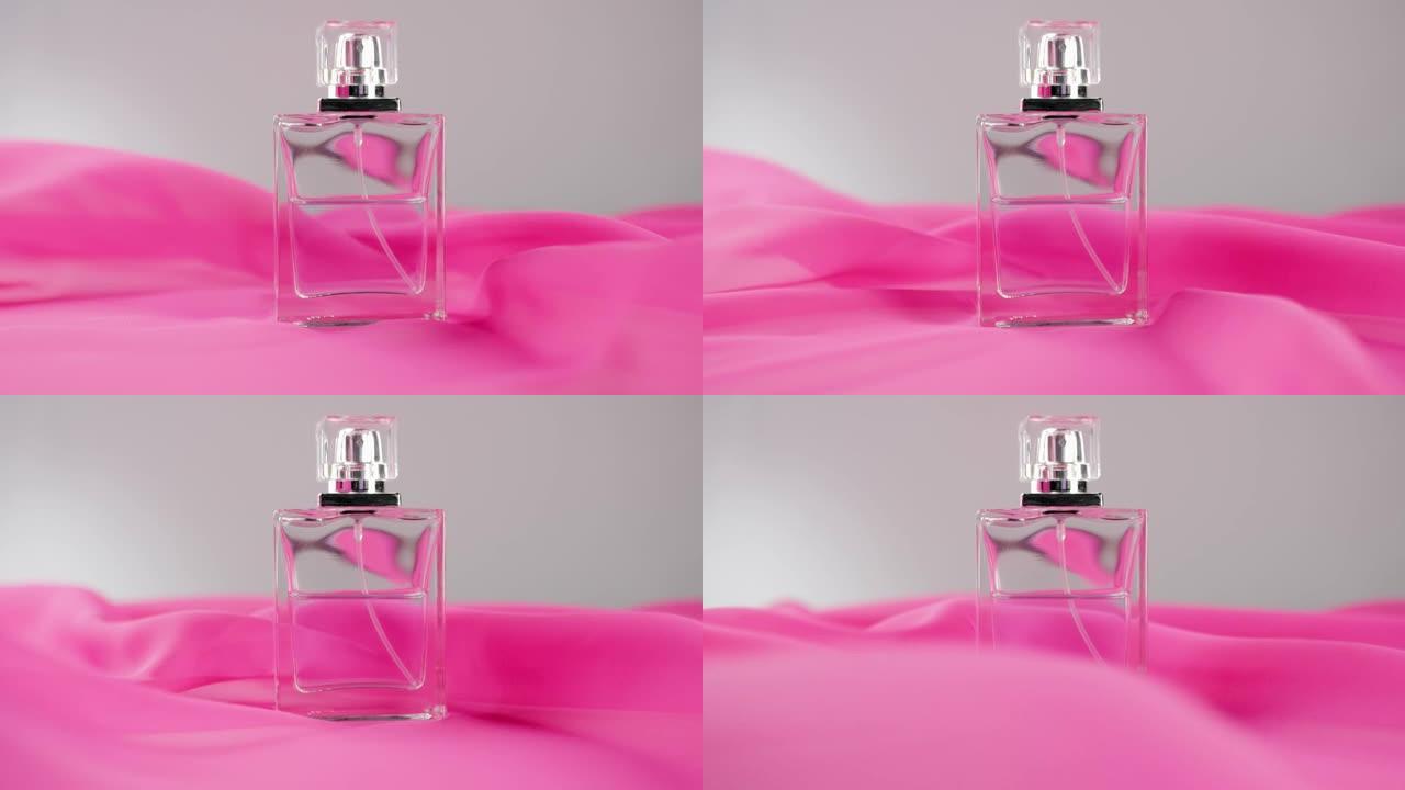 白色桌子上有青色香水或精油的扁平香水瓶。粉红色的织物四处飘动，香水瓶周围的空气中飘扬。香气和气味的概