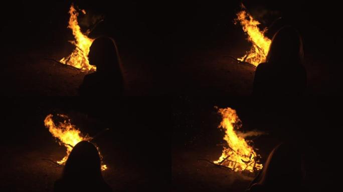 神秘女人的剪影在黑色背景的火飞焰，火花，轮廓轮廓。户外慢动作。高加索人。