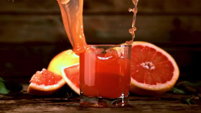 一块超级慢动作的葡萄柚掉入一杯带有飞溅的葡萄柚汁中。以1000 fps拍摄。