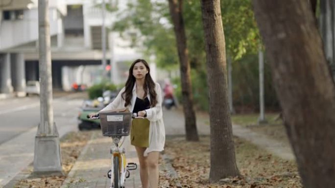 美丽的女孩骑着自行车在城市中旅行。