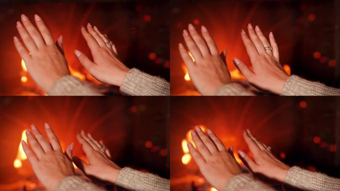 特写4k镜头，年轻女子在壁炉燃烧的火中温暖双手