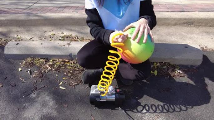 女人用空气压缩机给球充气。