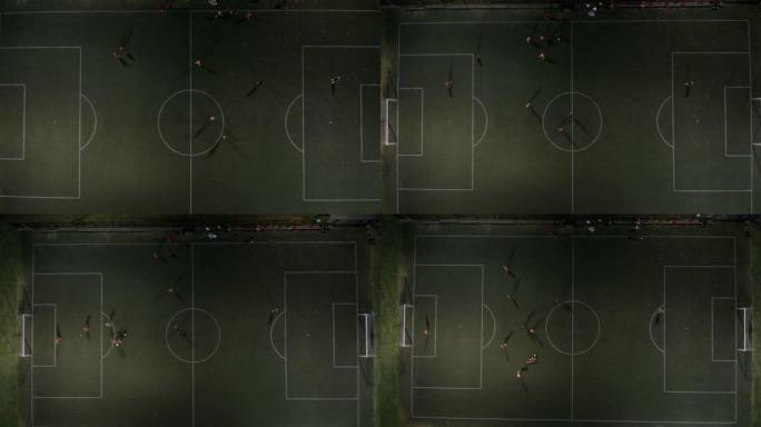 鸟瞰图的足球场在晚上和两队年轻的男孩教练踢足球。小男孩在夜间体育场鸟瞰图与教练踢足球。