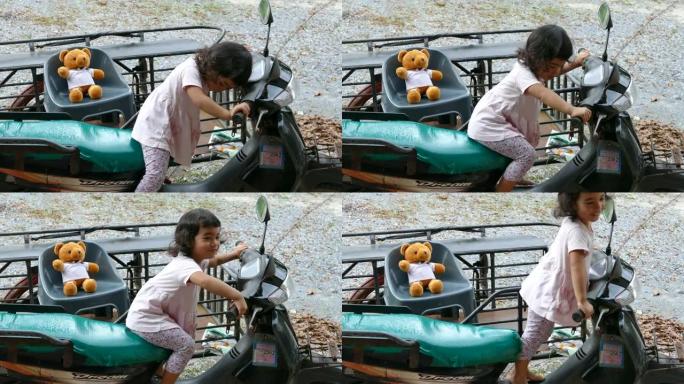 可爱的亚洲小女孩在摩托车上玩泰迪熊