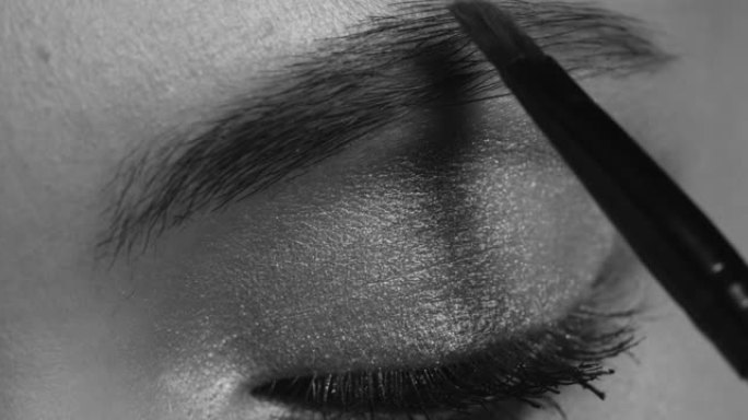 特写-女孩脸的一部分，她的眉毛是由化妆师画的。黑白视频。