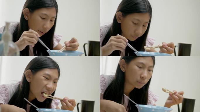 亚洲女孩一边看电影或病毒视频，一边在家吃热面条汤，生活方式理念。