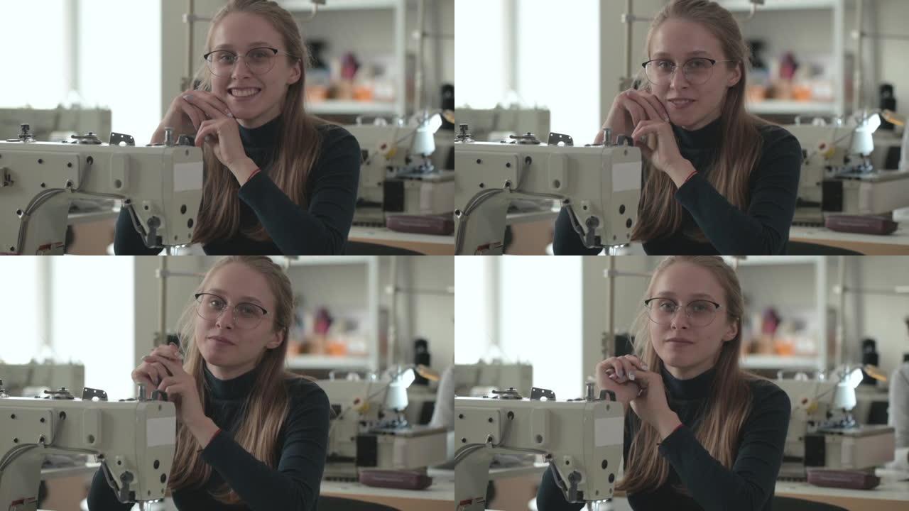 美丽的裁缝坐在工作场所，用电动缝纫机微笑着