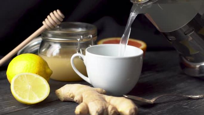 人正在倒入一杯含姜，柠檬和蜂蜜的维生素暖茶。在寒冷的日子或流感中有用和美味的茶的概念