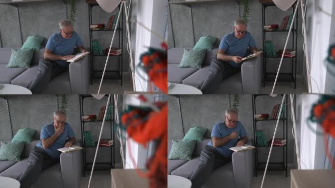 老人坐在沙发上看书，在家放松