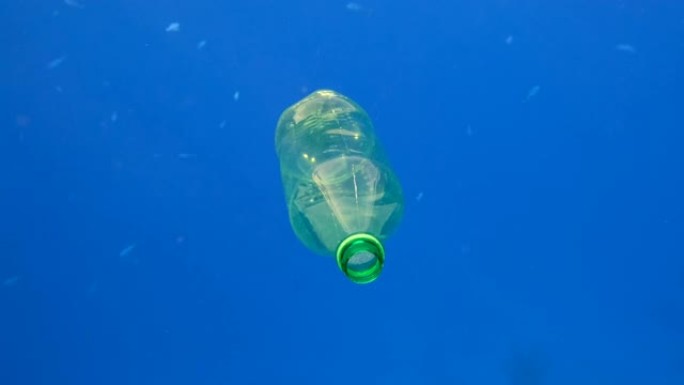 塑料污染，蓝色水中的塑料瓶。废弃的绿色塑料瓶在太阳的光线下慢慢漂浮在蓝色的水面下。红海塑料垃圾环境污