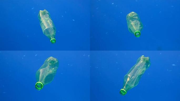 塑料污染，蓝色水中的塑料瓶。废弃的绿色塑料瓶在太阳的光线下慢慢漂浮在蓝色的水面下。红海塑料垃圾环境污