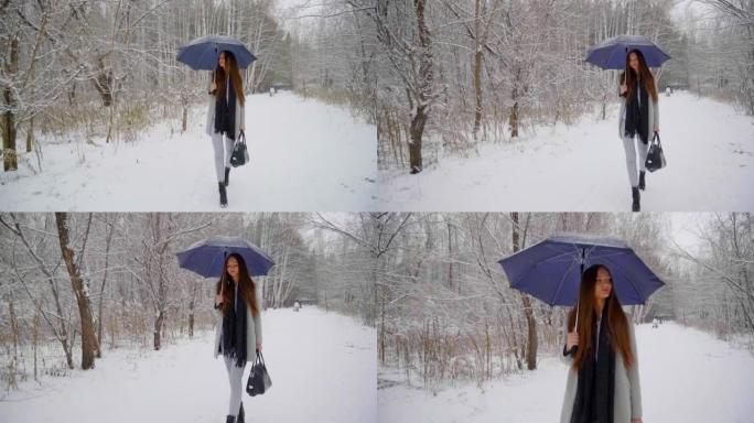 美丽的带伞的年轻女子正在冬季公园的户外散步。慢动作。年轻女子在白雪皑皑的背景上行走的时尚时尚冬季肖像
