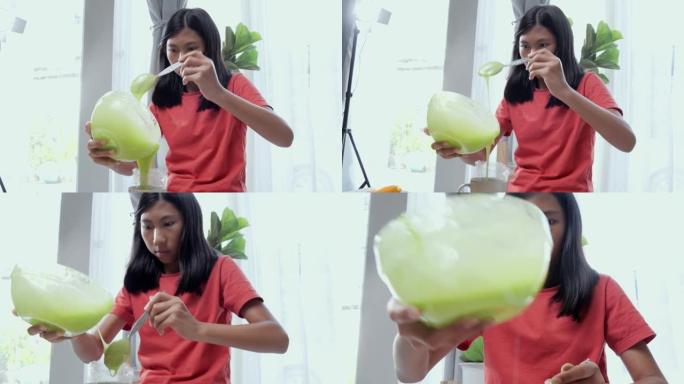 快乐的亚洲女孩你块茎通过智能手机制作视频，在家烹饪一些甜蜜的零食，生活方式概念。
