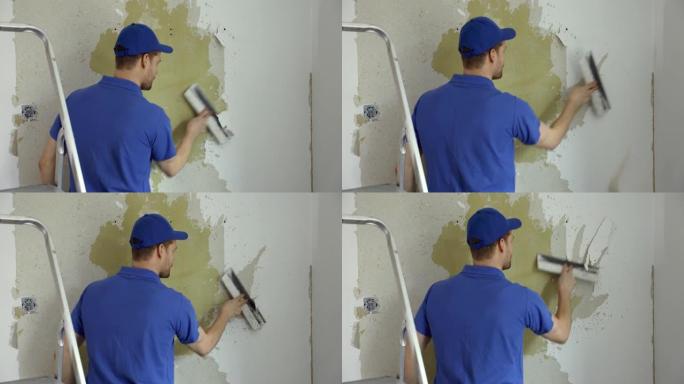 工人从墙上取下旧的油漆墙纸。房屋装修内部更新
