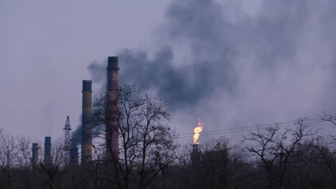 黄昏中深蓝色天空背景下的工厂管道烟雾