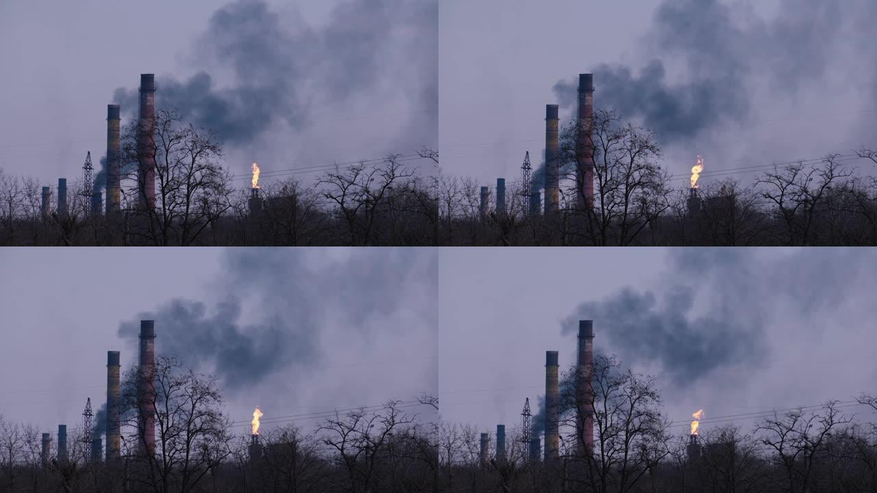 黄昏中深蓝色天空背景下的工厂管道烟雾