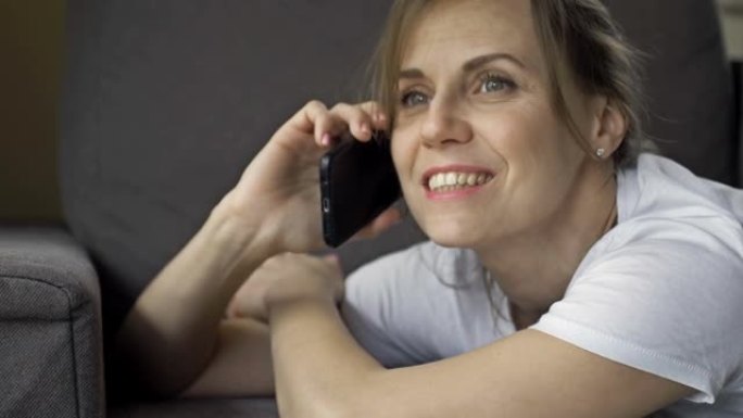 一个美丽的中年妇女在手机上聊天的肖像。女人脸上洋溢着幸福的笑容。她看起来像是恋爱了