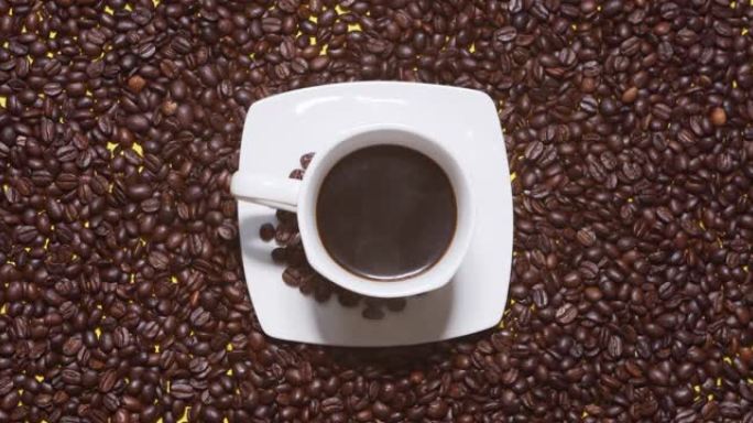 咖啡豆背景上的杯咖啡。男性的手以慢动作从白色的碟子中拿出一杯黑咖啡。