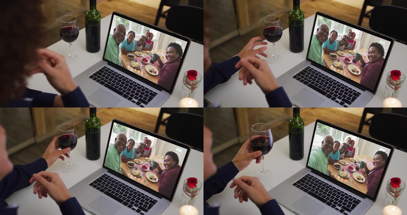 非裔美国妇女在家里用笔记本电脑进行视频通话时喝葡萄酒的中间部分