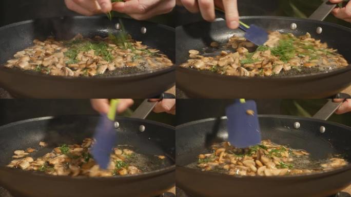 厨师的手在煎锅里把绿色莳萝扔进炸蘑菇的特写镜头。