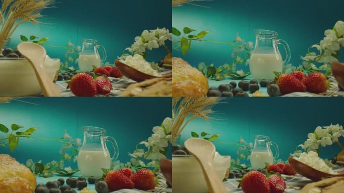 4k精美的装饰桌子组成，带有牛奶乳制品，面包店，浆果，蓝色背景上的花朵。在慢动作的ARRI相机上近距