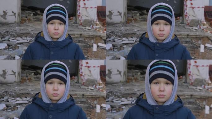 一个无家可归的男孩站在废墟的背景上，忧伤地看着镜头。一个无家可归的孩子，流浪儿