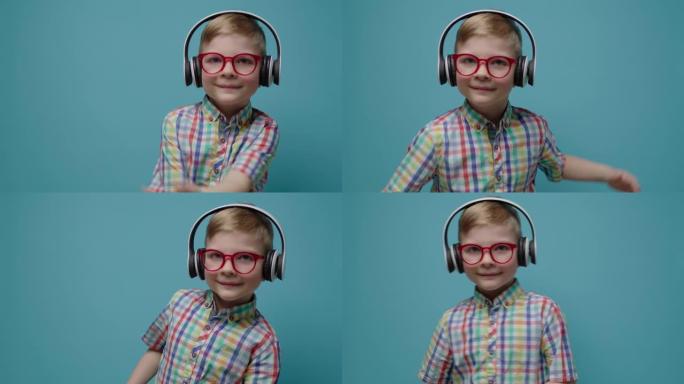戴着眼镜和耳机的微笑可爱的男生在慢动作的蓝色背景上跳舞。快乐的孩子看着相机跳舞。