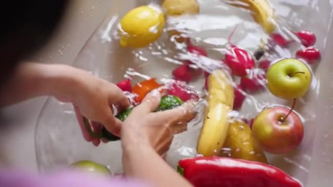 女性手洗黄瓜辣椒番茄香蕉梨苹果柠檬。手洗新鲜蔬菜水果用水在盆中慢动作。素食。新鲜收获。洗水果和蔬菜。