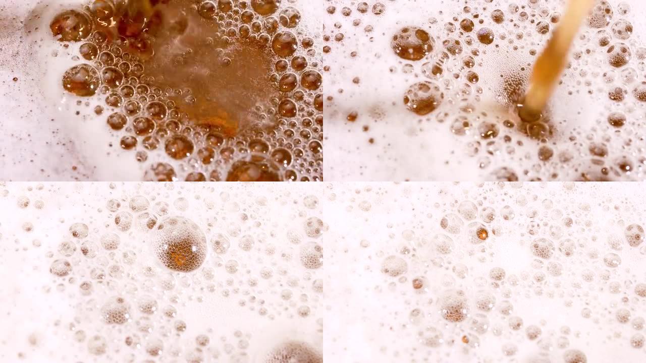 轻啤酒倒入玻璃杯的俯视图。将精酿啤酒倒入杯子中，形成致密的白色泡沫，并形成气泡。新鲜度和泡沫。慢动作
