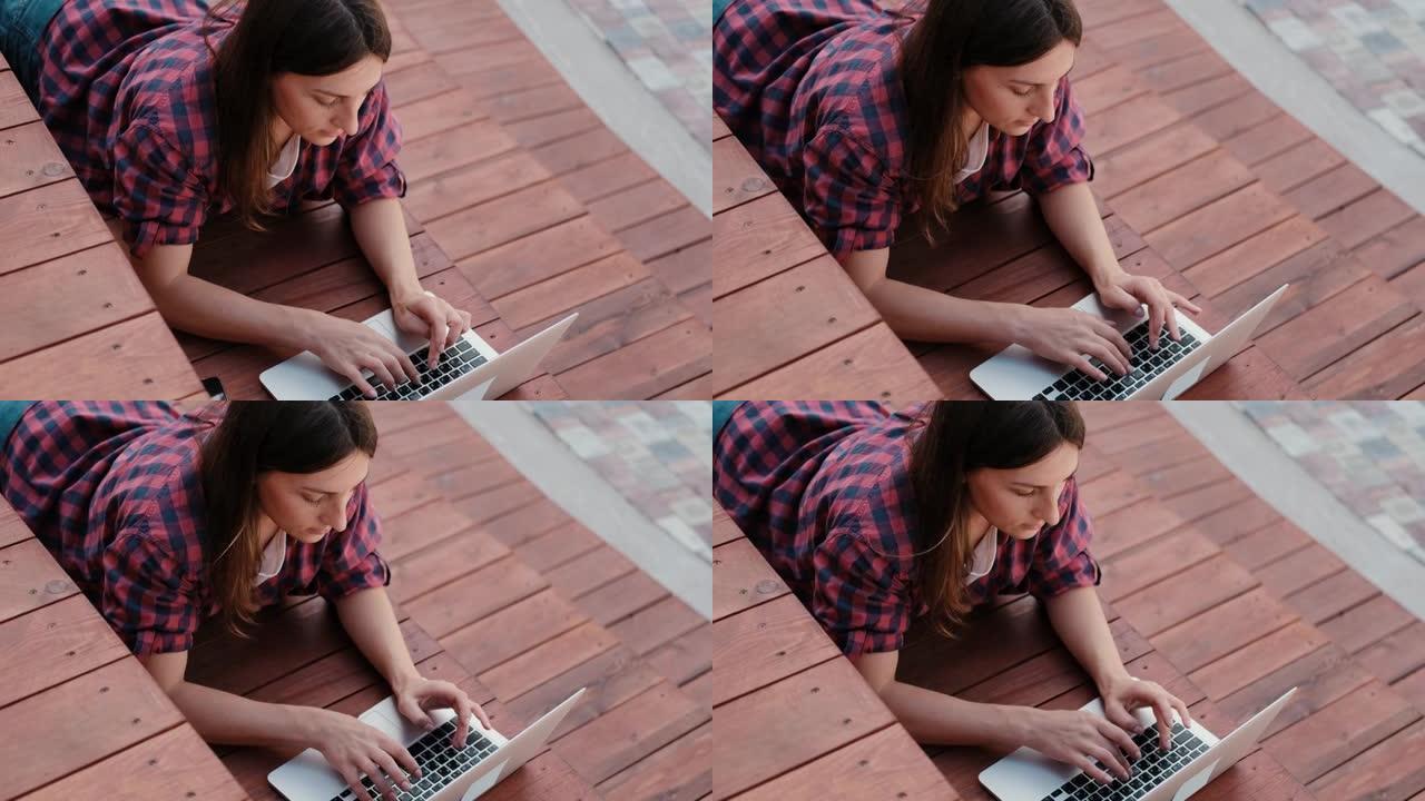在新鲜空气中在笔记本电脑上工作的女孩。满意的年轻女性自由博客作者在她的博客上发表文章