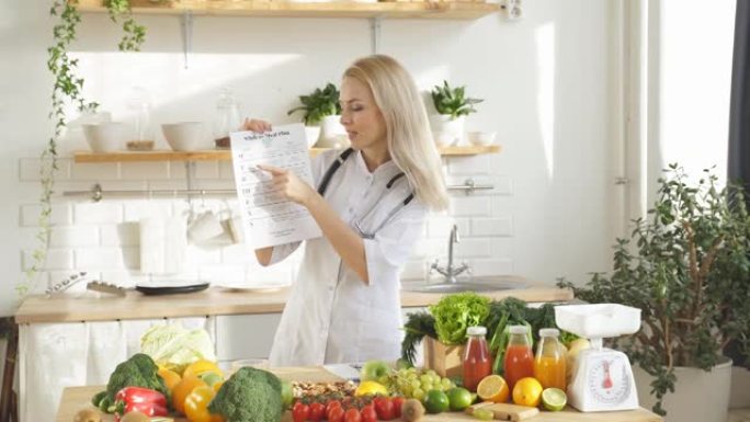 女人站在一张有很多纯素食成分的桌子旁，她在厨房里谈论家里的适当营养