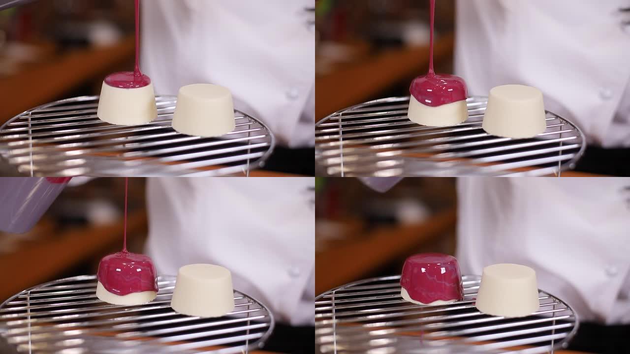 糕点厨师将镜子糖霜倒在蛋糕上。红釉从架子上流下。在厨房工作的专业糖果制造商
