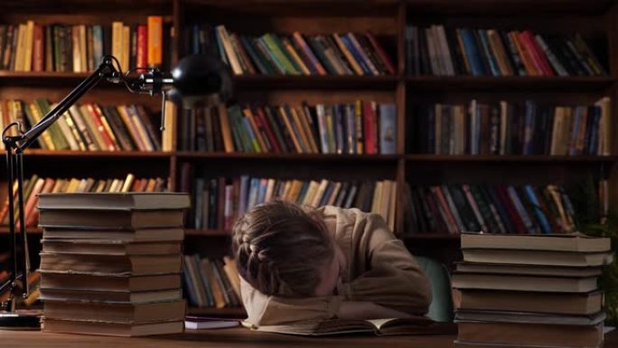 疲倦的女学生睡在桌上的书中的抄写簿上
