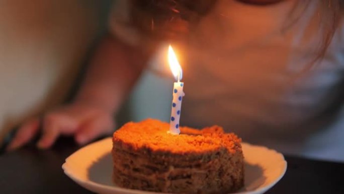 可爱的小女孩在生日蛋糕上吹蜡烛