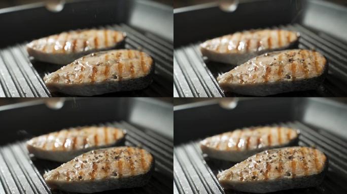 新鲜的三文鱼排在油锅中油炸。在黑色背景上